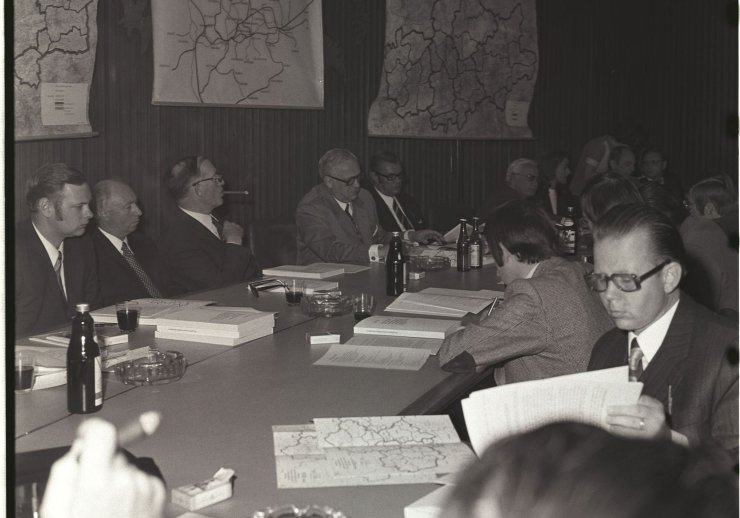 Mehrere Männer an einem Konferenztisch in den 1970er Jahren