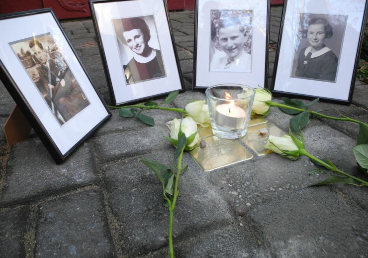 Vier Stolpersteine mit Kerzen, Rosen und Lichtern